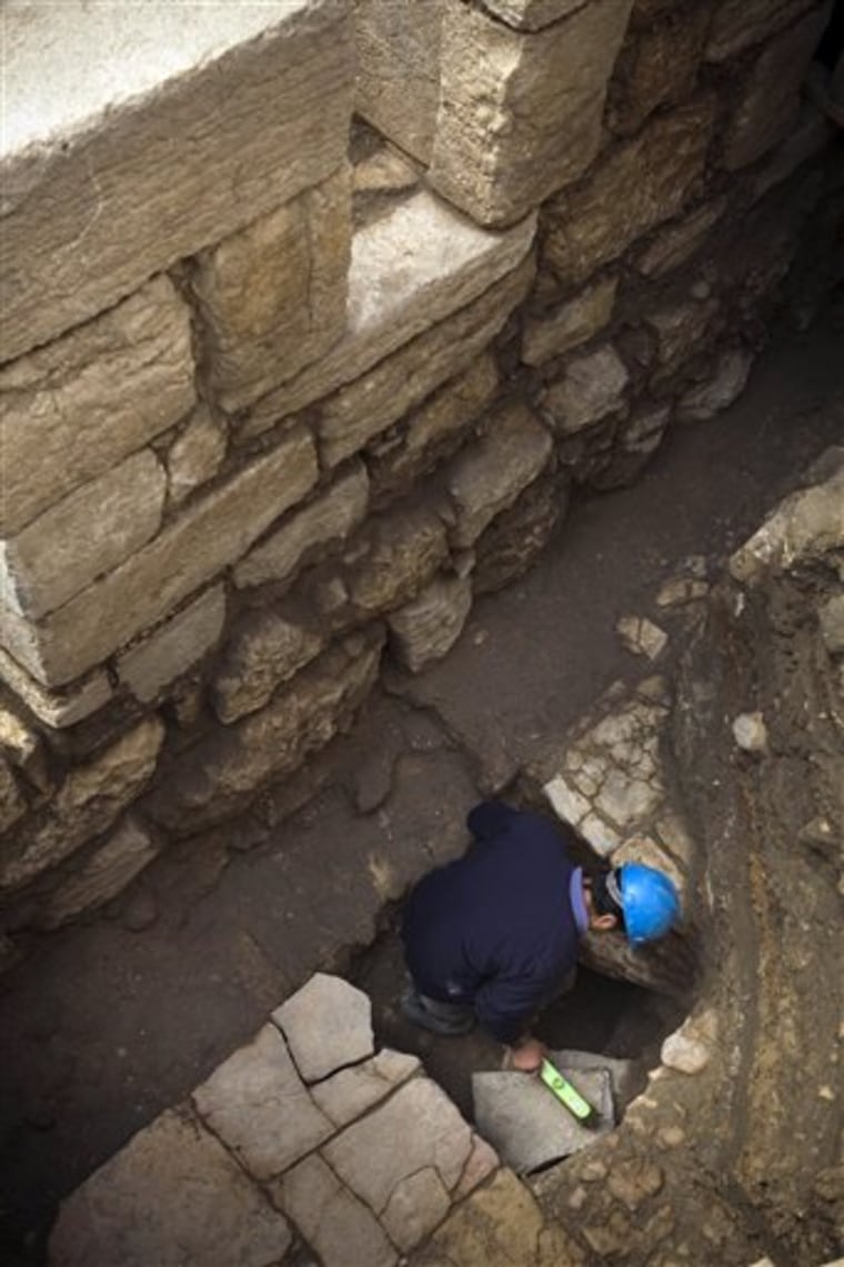 A worker cleans a stone in a 1,500-year-old street located 4.3 meters (14 feet) below ground level, revealed by the Israeli Antiquities Authority in the old city of Jerusalem.
